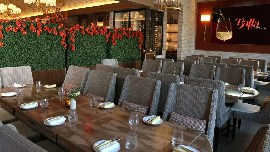 Contemporary restaurant dining area with plant wall, wine cellar, and Balla logo.