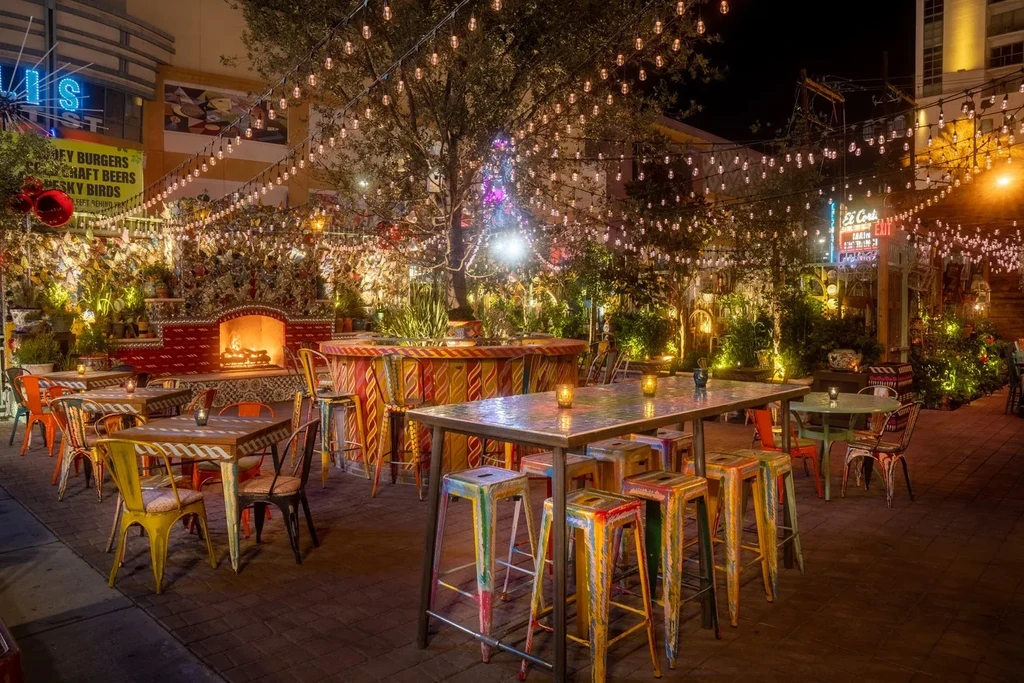 Empty, colorful outdoor patio with string lights and a glowing fireplace.