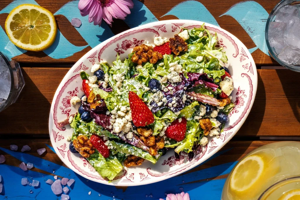 Vibrant berry, cheese, walnut salad on a rustic table.