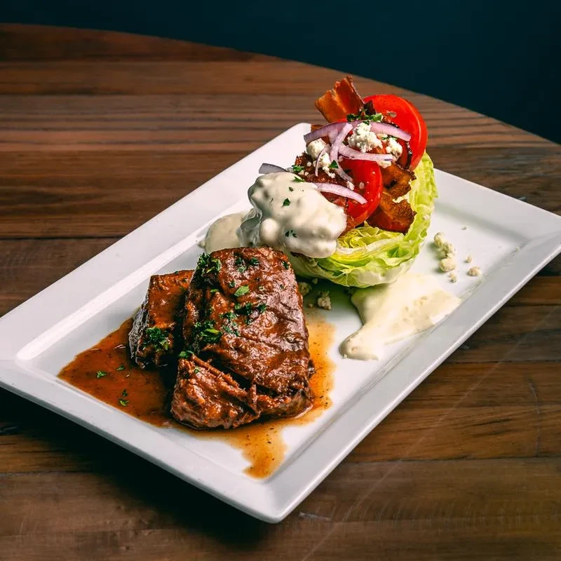 Braised meat and wedge salad on a rectangular white plate.