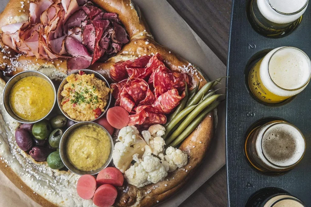 Pretzel platter with cold cuts, pickled vegetables, dips, and a beer flight.