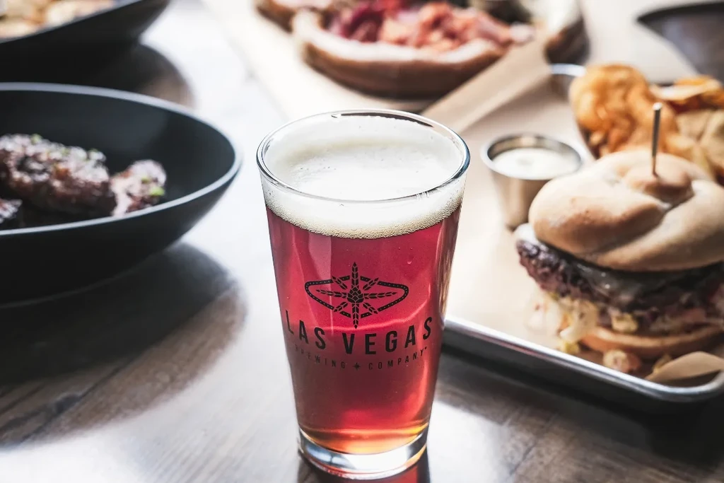 Las Vegas Brewing beer pint, with blurred burger and meat.