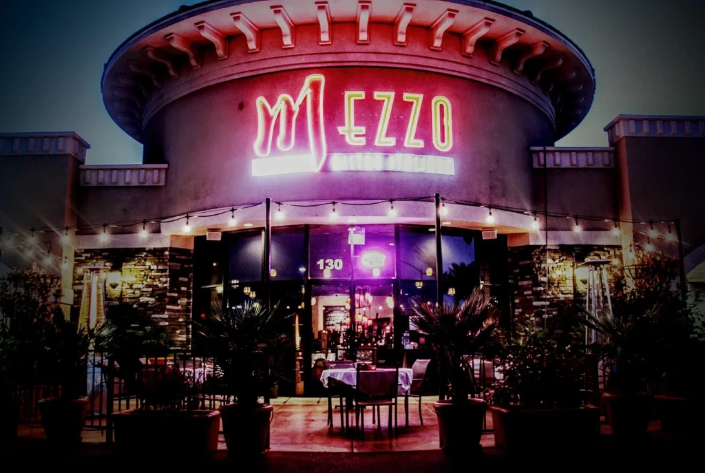 Neon-lit "MEZZO Italian Restaurant" exterior at night with patio.