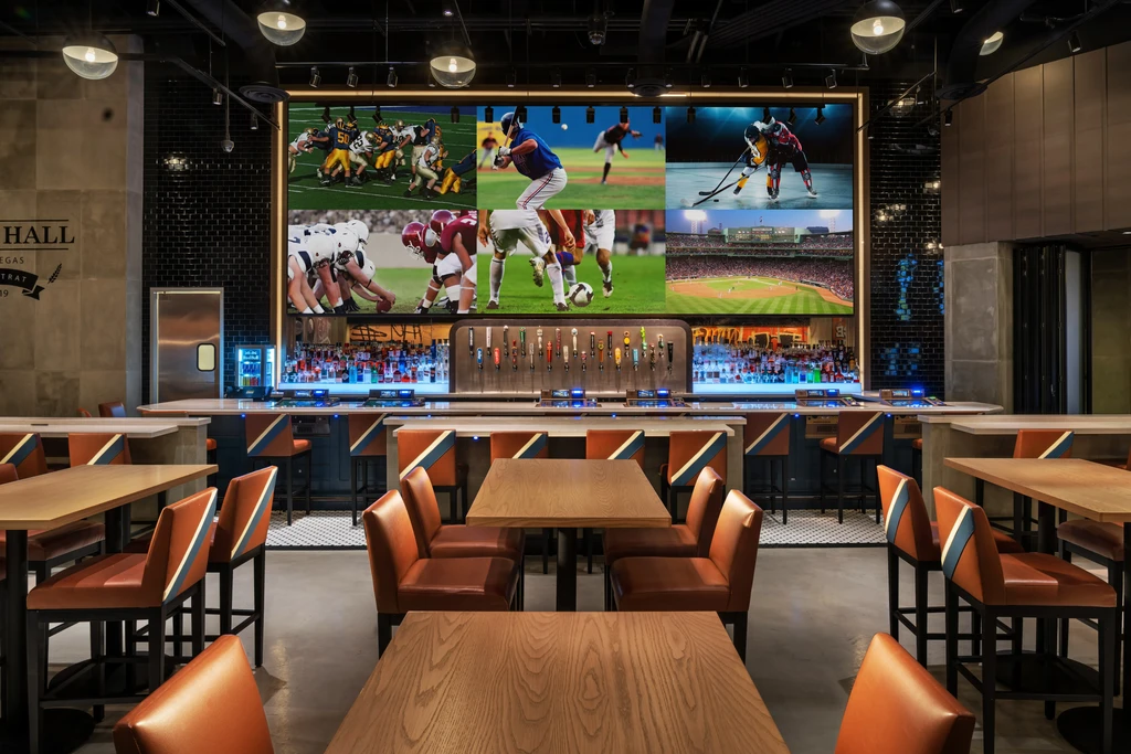 Modern sports bar interior with large video wall displaying sports.