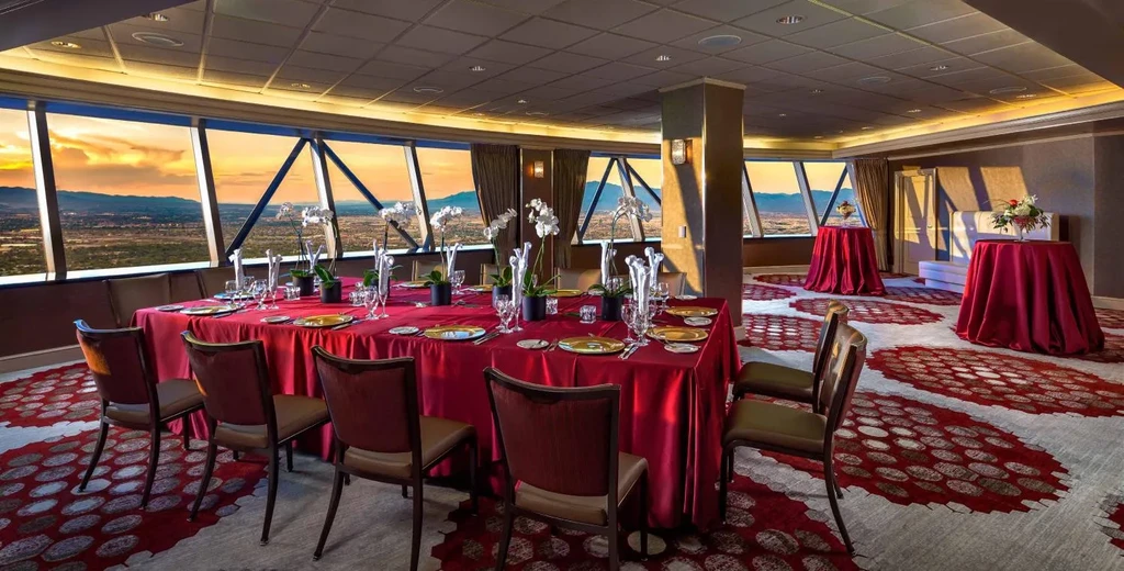 Luxurious dining table with red tablecloth, orchids, cityscape sunset view.