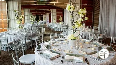 Elegant formal dining room with round tables and white floral centerpieces.