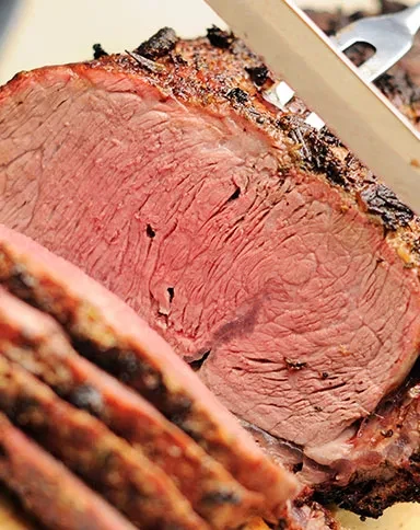 Slicing medium-rare roasted meat, showing a dark crust.