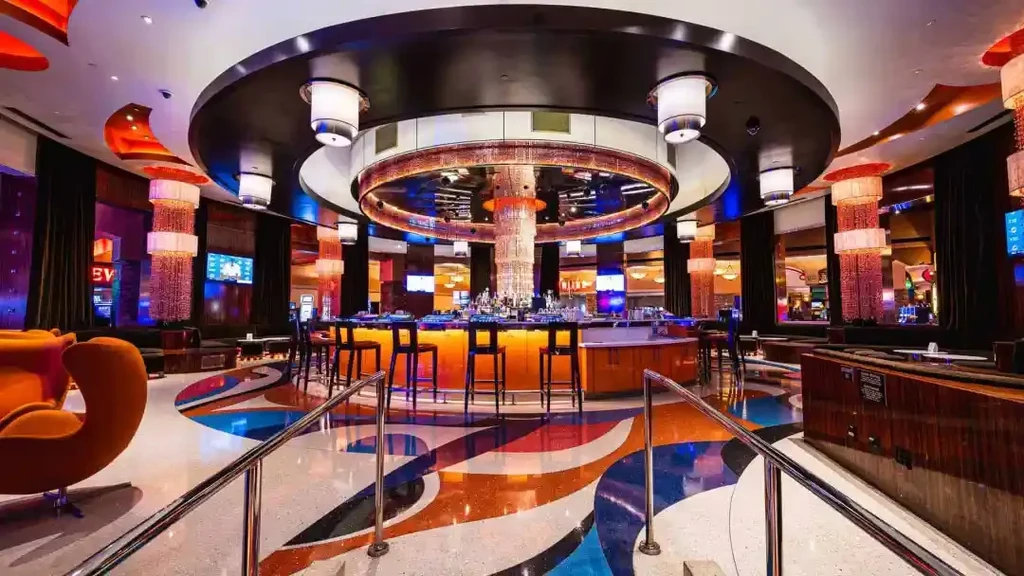 Vibrant modern bar with circular counter, multi-tiered chandelier, and abstract floor.