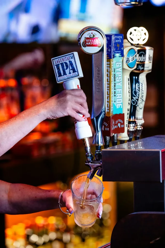 Close-up of hand pouring Lagunitas IPA from a bar tap.