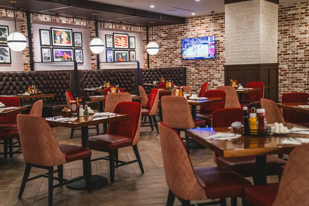 Empty casual dining restaurant with booths, brick walls, and TV.