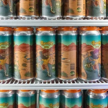 Multiple blue and orange Hypathon IPA beer cans with desert labels.