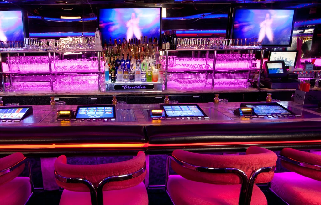 Sleek bar with digital gaming, liquor bottles, and vibrant LED lighting.