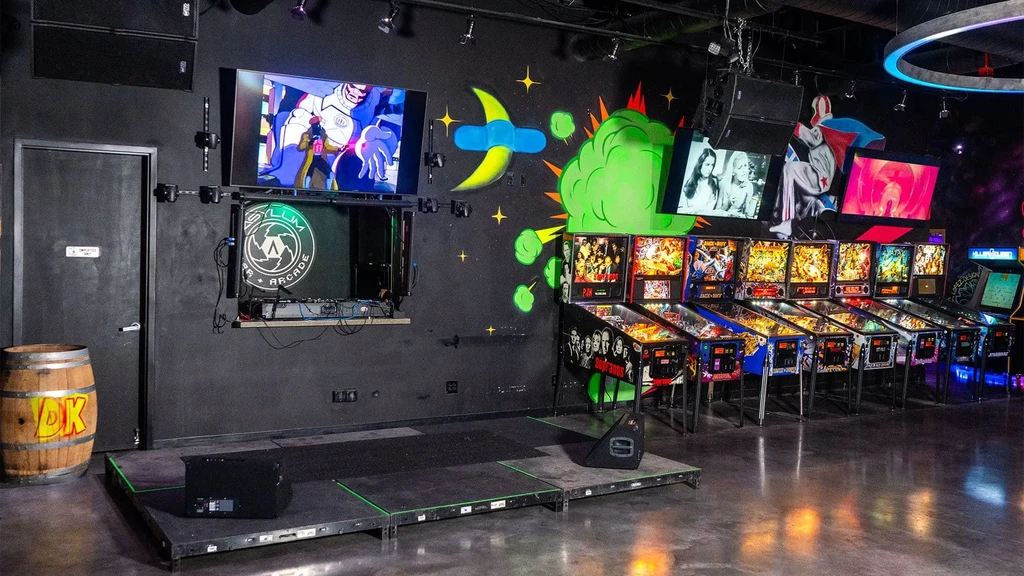 Asylum Arcade interior with pinball machines, screens, and pop-art murals.