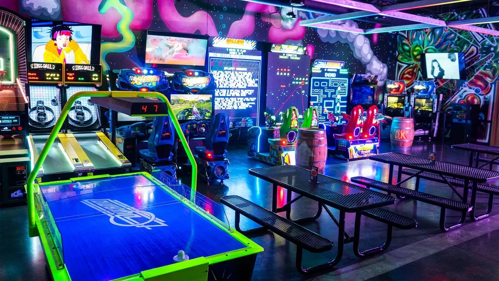 Neon-lit bar-arcade with air hockey, Skee-Ball, and colorful murals.