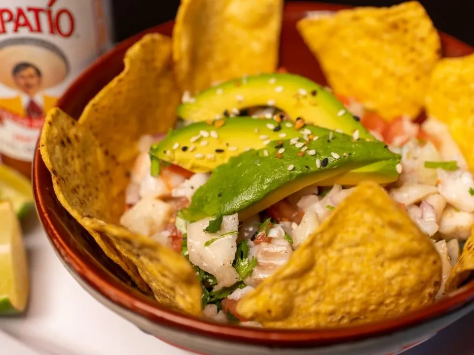 Vibrant bowl of seafood ceviche with avocado, cilantro, and tortilla chips.