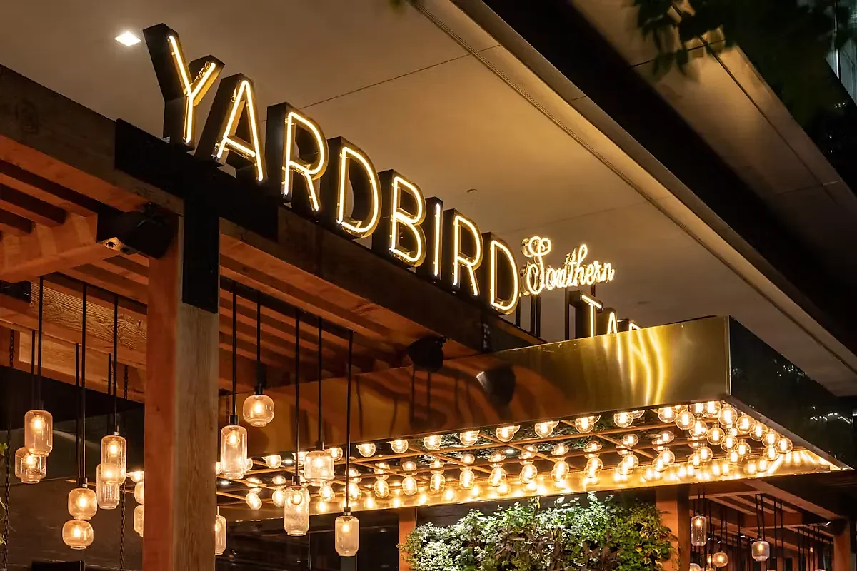 Illuminated Yardbird exterior signage above entrance with hanging jar lights
