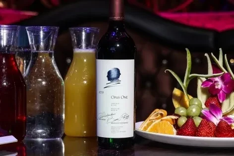 Opus One 2019 wine, colorful carafes, and fresh fruit platter with orchids.
