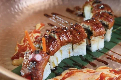 Elaborately presented sushi roll with unagi, decorated like a creature's head.