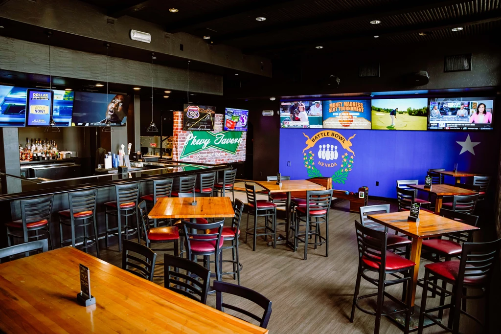 Empty modern sports bar with tables, bar, and multiple TVs.