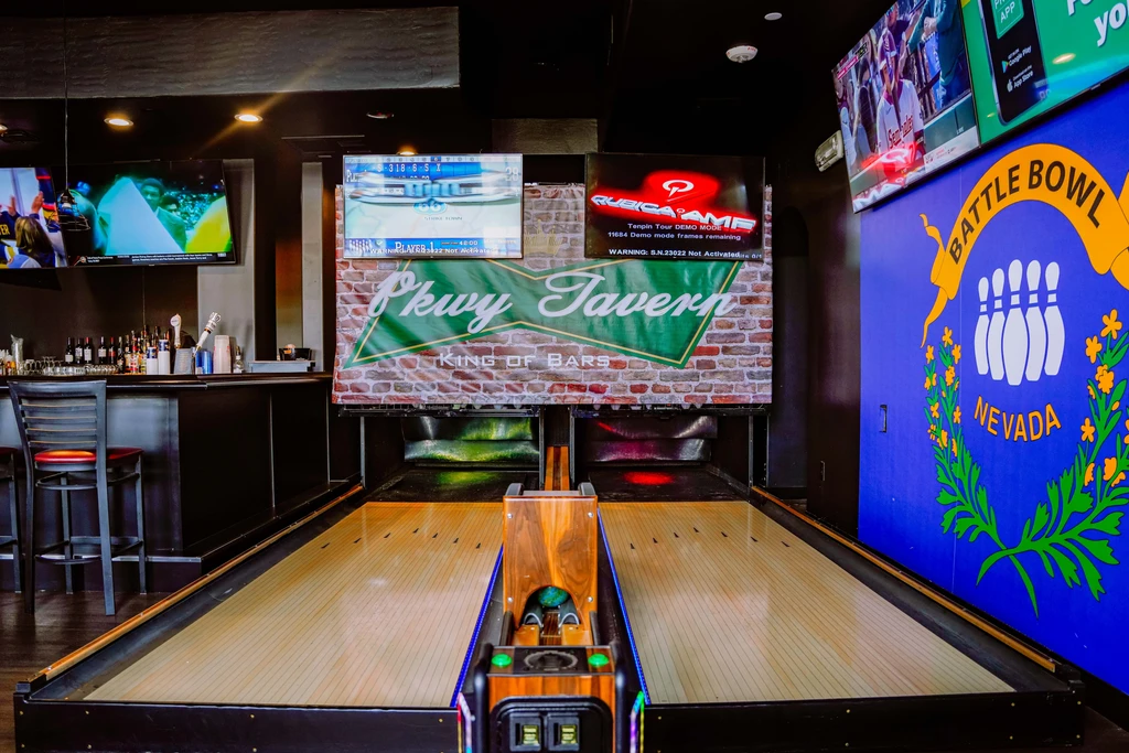 Pkwy Tavern interior showing shuffleboard, bowling mural, and multiple screens.