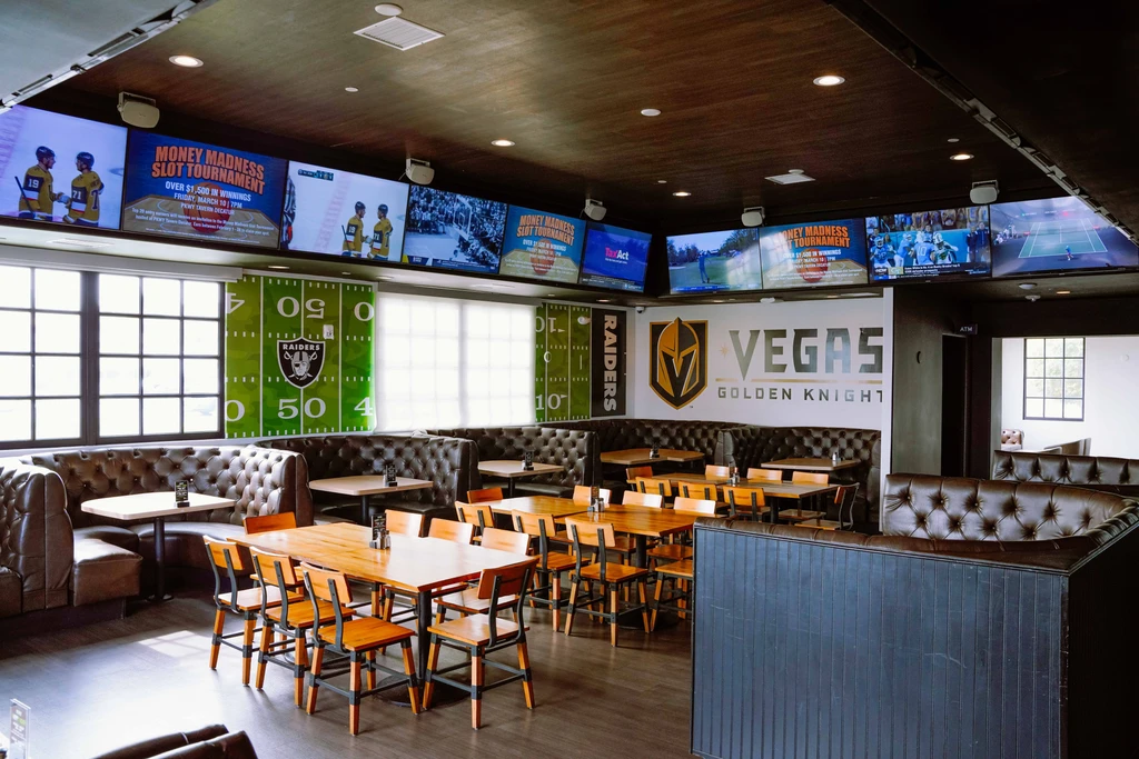 Modern sports bar interior featuring booths, wooden tables, and multiple large TVs.