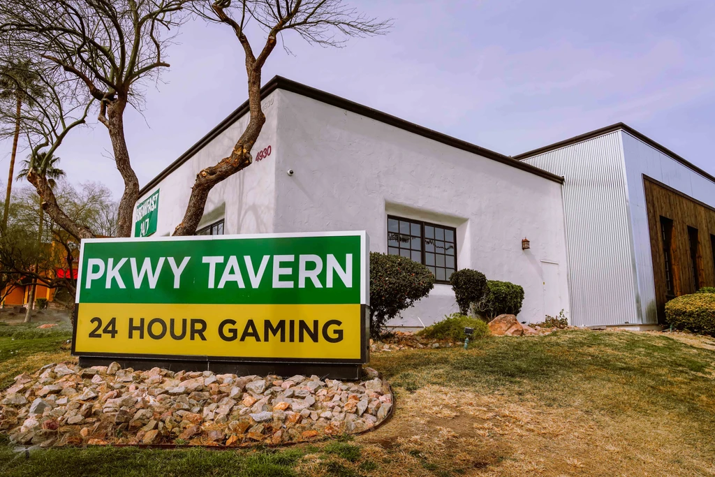 White stucco PKWY TAVERN building with a prominent green and yellow sign.