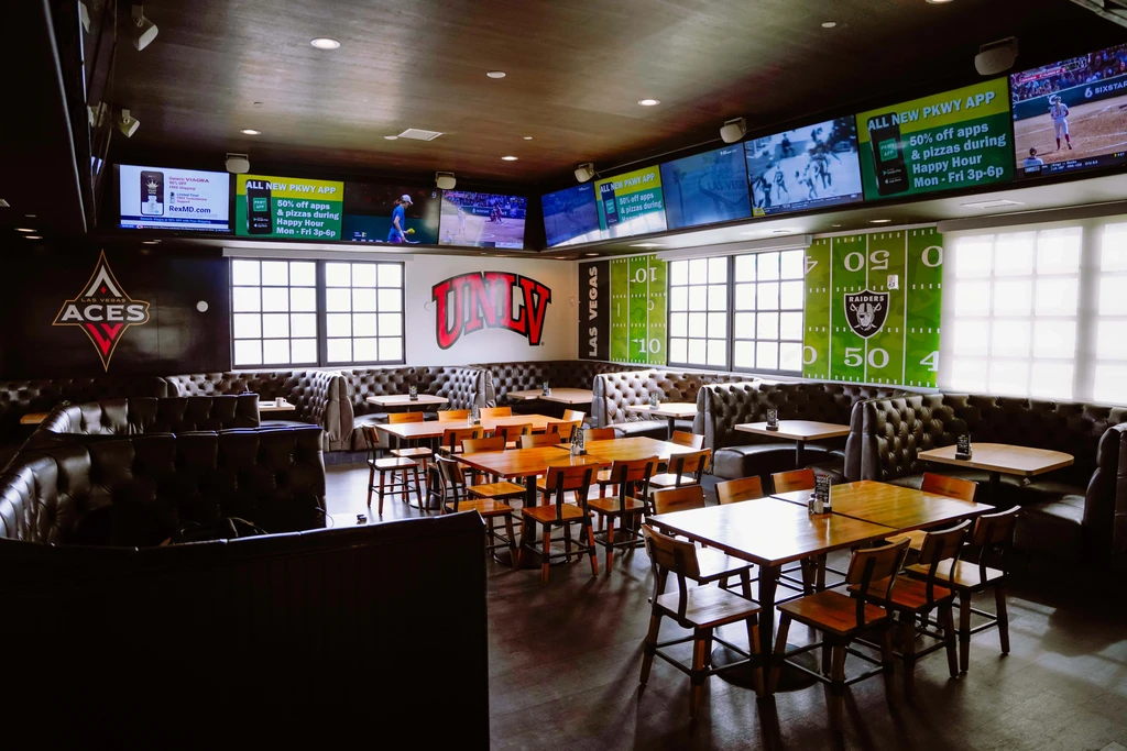 Spacious sports bar interior with many large TVs and sports decor.