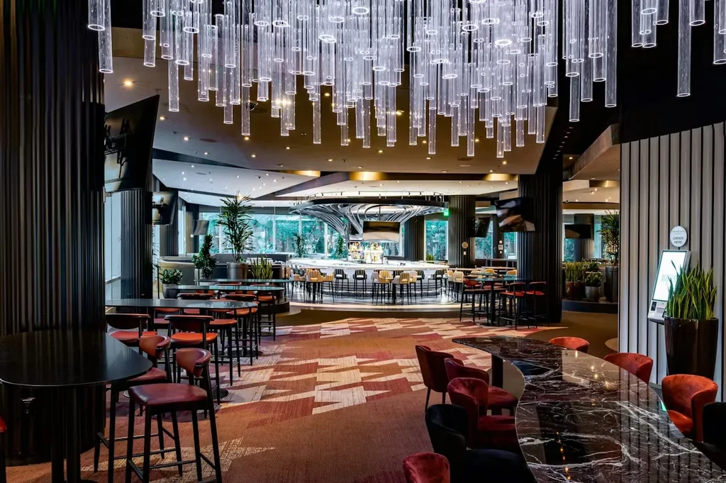 Modern restaurant interior with round bar, velvet chairs, and tube chandelier.
