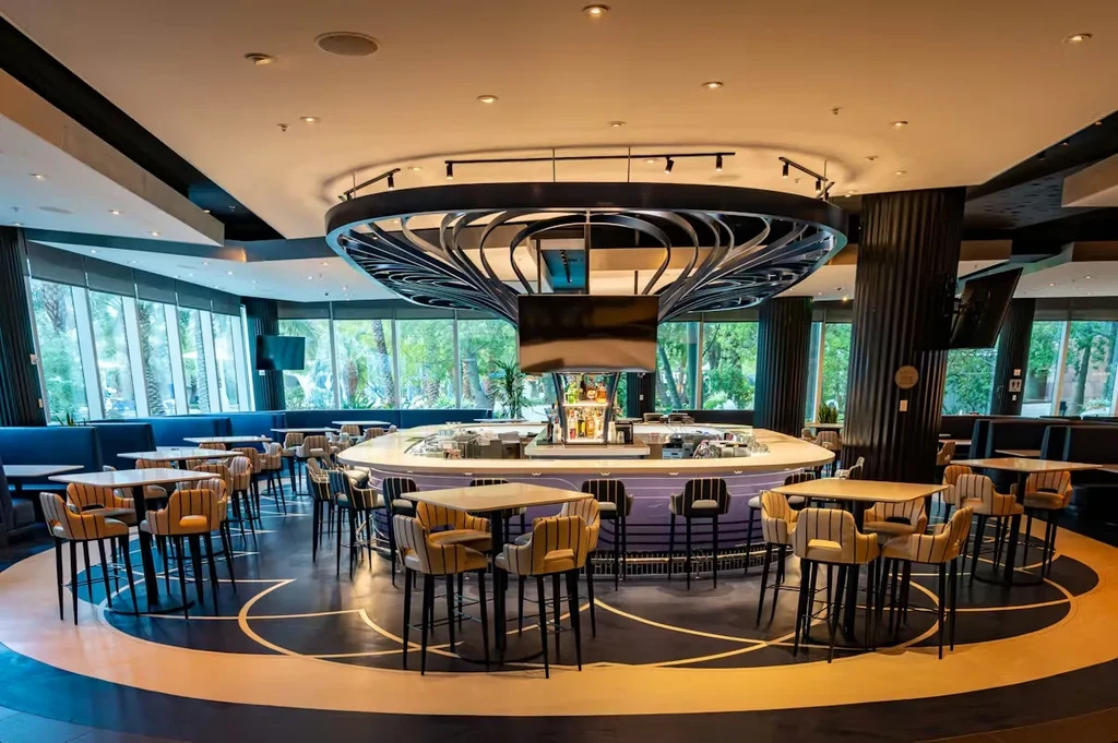 Modern, empty bar lounge with an oval bar and patterned circular floor.