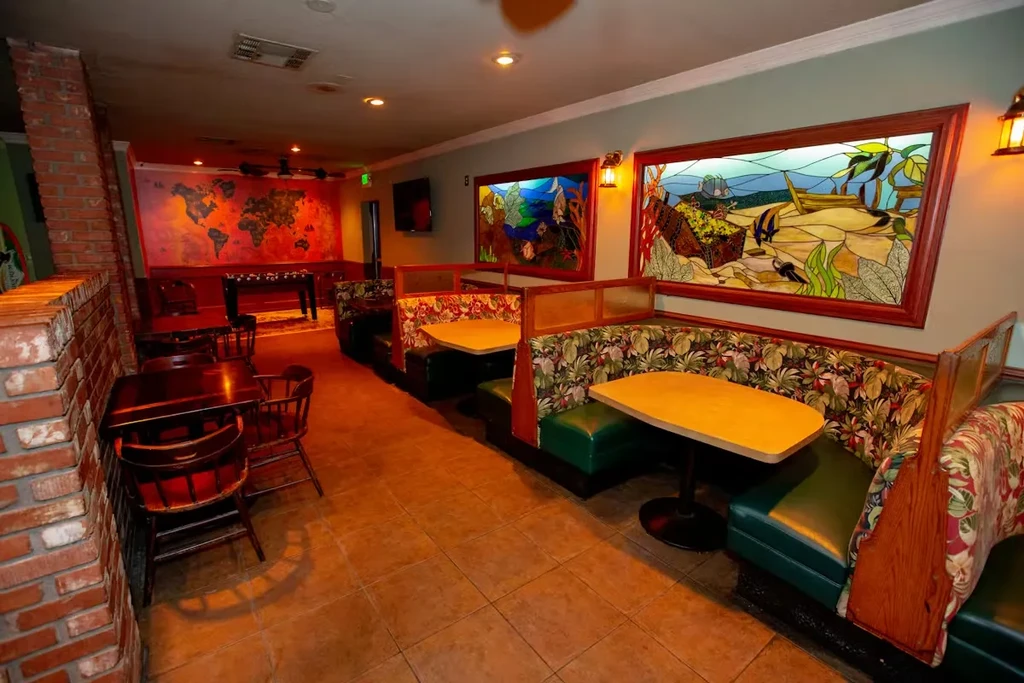 Restaurant interior: floral booths, stained glass art, world map mural.