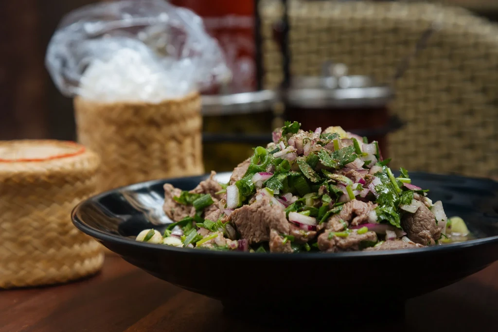 Sliced meat salad with herbs, roasted rice, and sticky rice.
