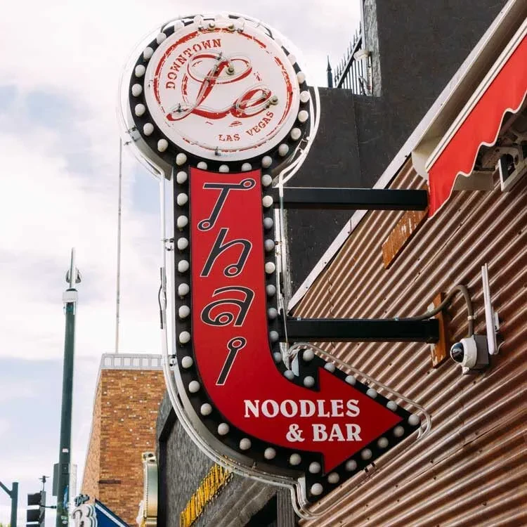 Vintage red and white neon arrow sign for a Thai restaurant.