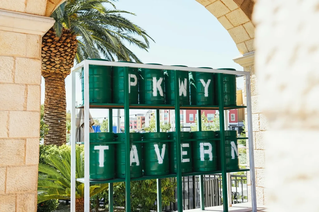 Green barrels spelling PKWY TAVERN viewed through a stone archway.