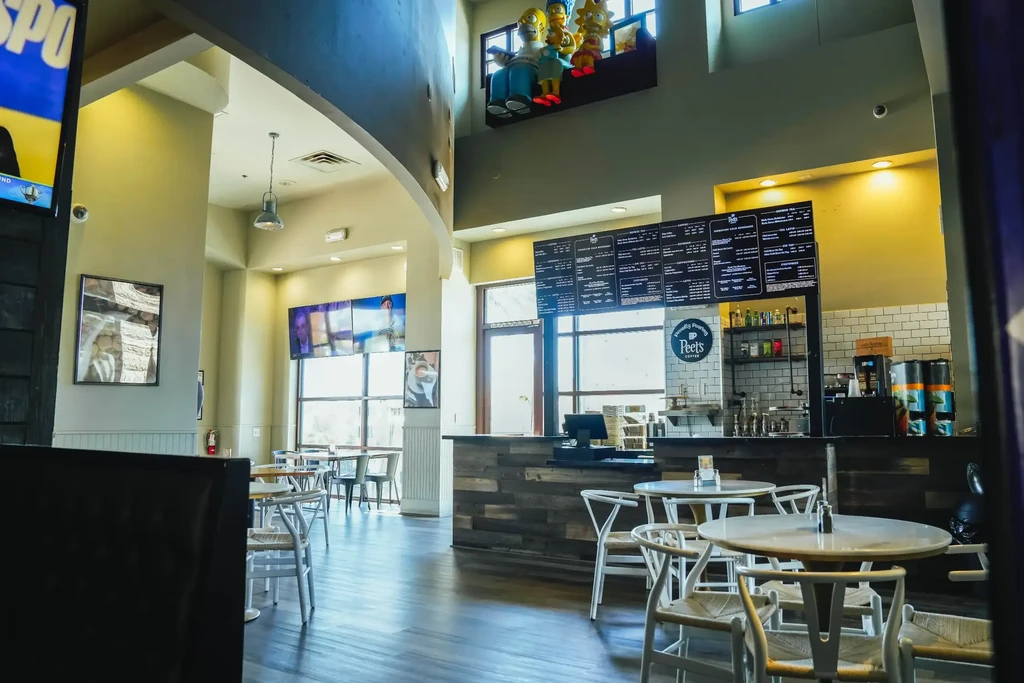Bright, modern cafe interior with wishbone chairs, rustic counter, Peet's Coffee.