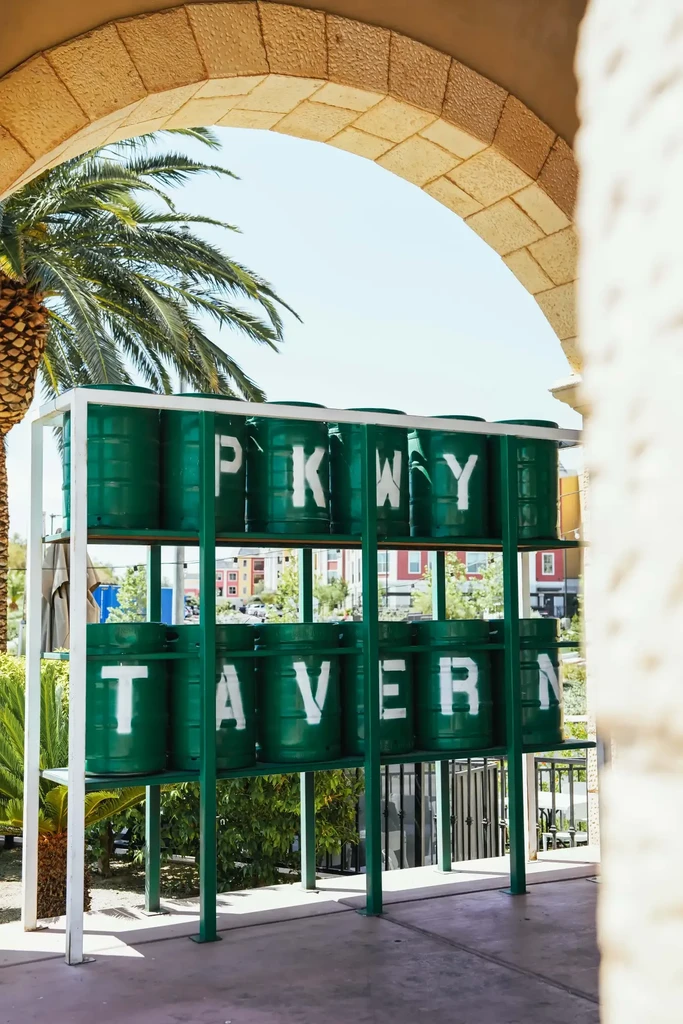 Green barrel sign for PKWY TAVERN framed by stone archway.