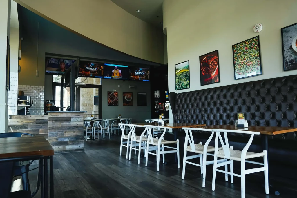 Clean, modern restaurant dining area with booths, bar, and TVs.