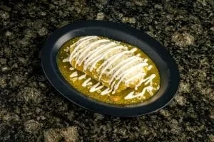 Oblong dish with green sauce and white zigzag on a dark plate.