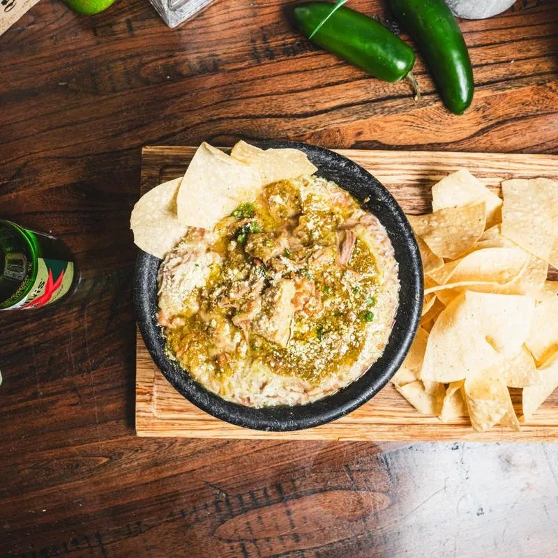 Creamy dip with green salsa, white cheese, and tortilla chips.