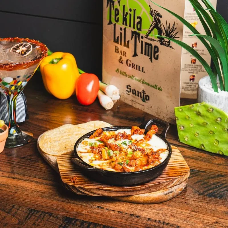 Skillet of melted cheese and spiced meat, tortillas, margarita, and restaurant branding.