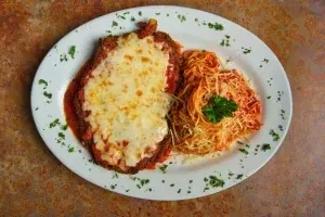 Breaded cutlet with melted cheese and red sauce, served with spaghetti.