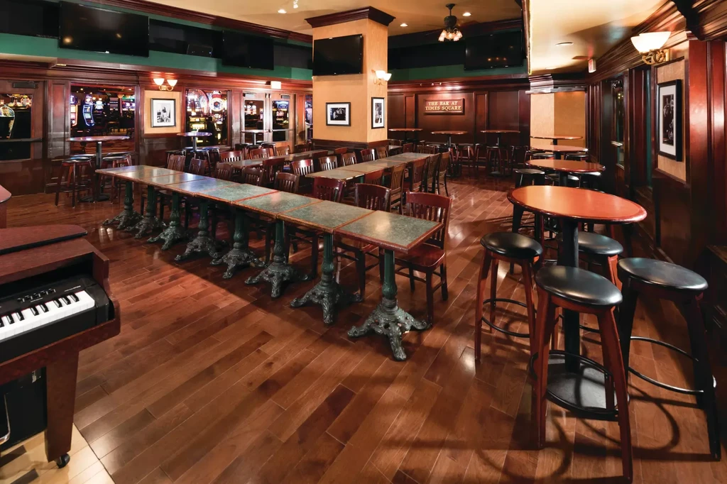 Empty "THE BAR AT TIMES SQUARE" bar showing tables, piano, and casino.