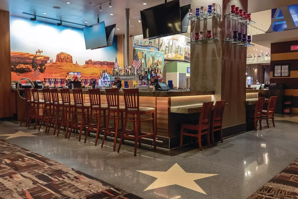 Brightly lit bar with desert mural, bar stools, American flags, and star floor.