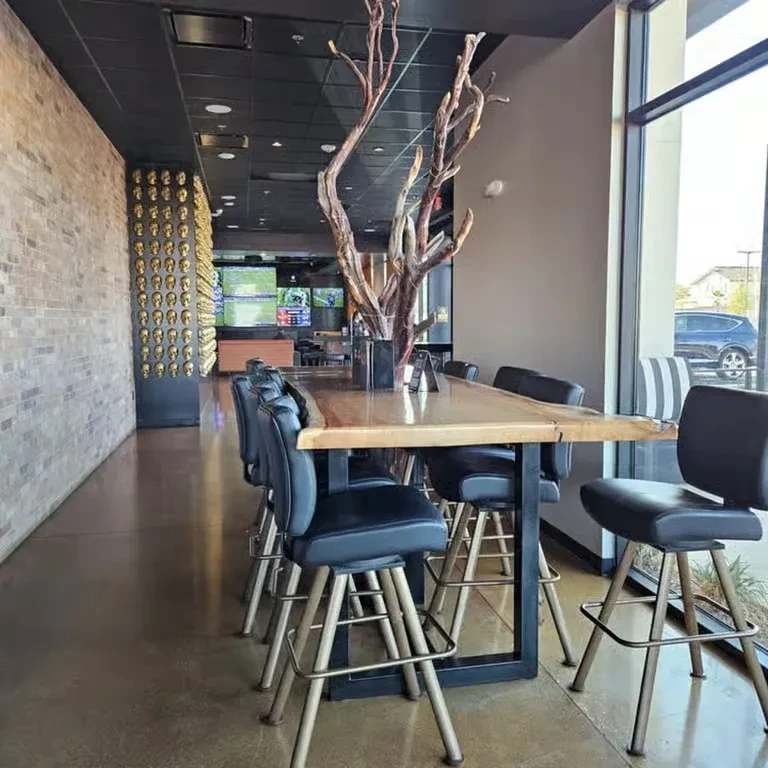 Modern restaurant interior with a live-edge wooden table and bare branches.