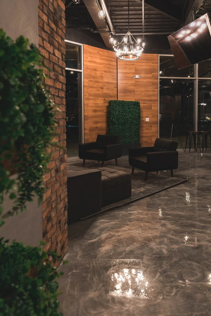 Modern industrial-chic lounge with green wall, concrete floor, and seating.