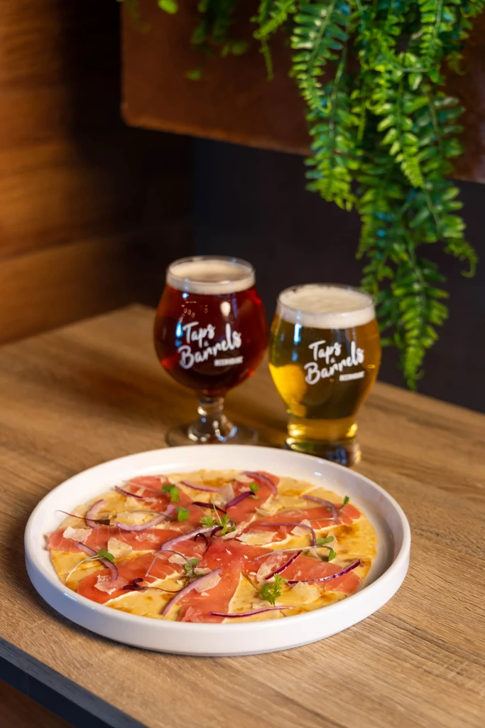 Flatbread with cured meat and two Tap's Barrels branded beers.