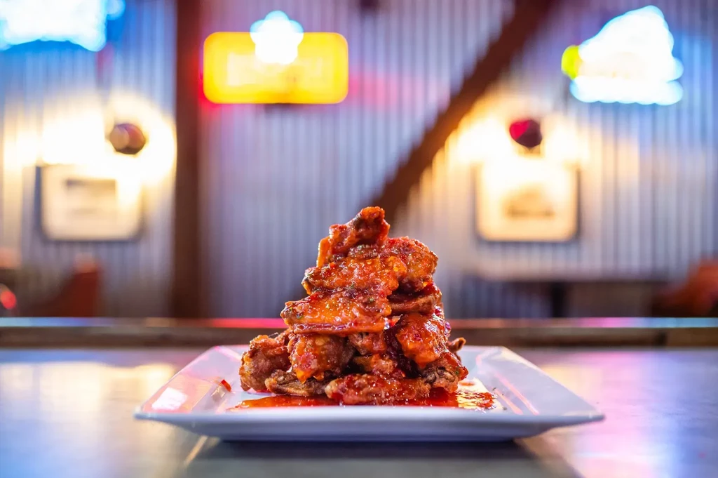 Deep-fried chicken wings coated in glossy reddish-orange chili sauce.