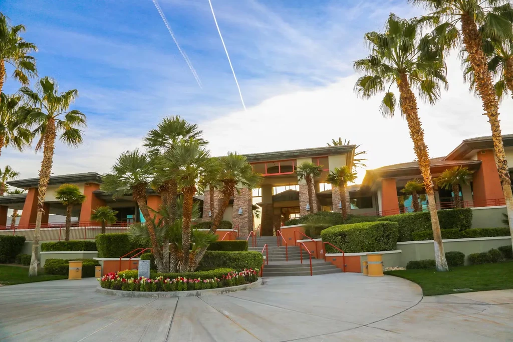 Grand terracotta building entrance with wide stairs and lush palms.