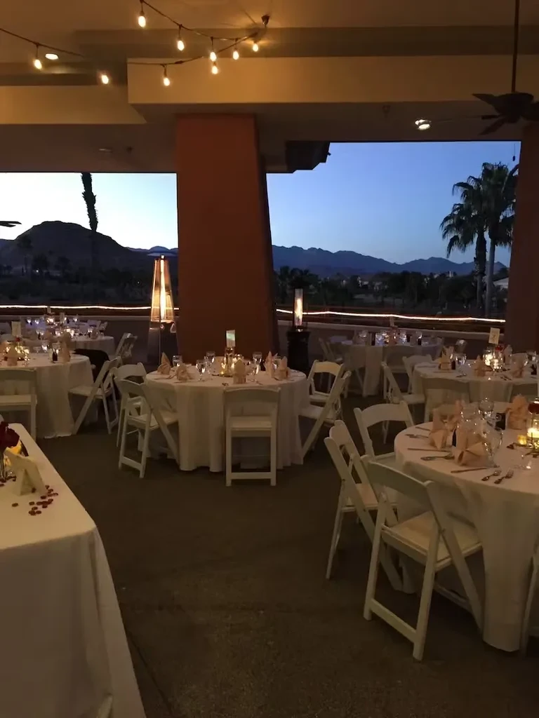 Outdoor dining tables set with string lights, heaters, and twilight mountain view.