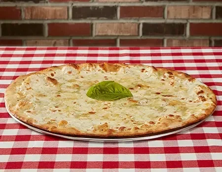 White pizza with melted cheese and basil on a checkered tablecloth.