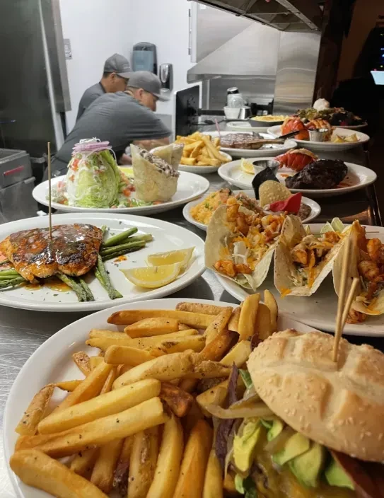 Variety of prepared dishes on a busy kitchen counter with staff.
